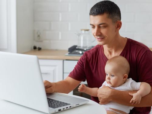 Dad on computer while holding his child